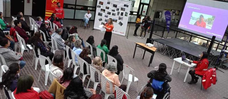 vista desde arriba del evento donde se ve la presentadora hablando frente a varias mujeres que asisten y están sentadas en silllas