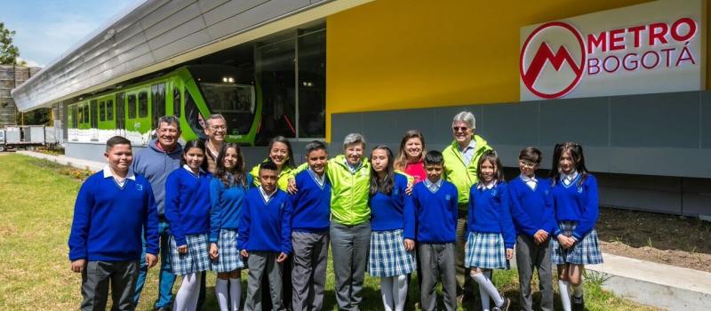 La alcaldesa Claudia Lopez y el gerente del Metro, Leonidas Narváez, posando afuera del vagón escuela junto a niños de un colegio